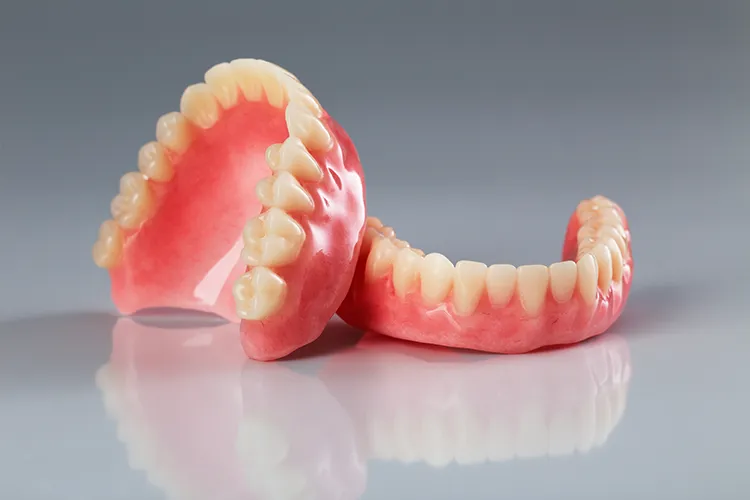 Pair of dentures on a reflective surface - Harmony Family Dentistry in Vancouver WA