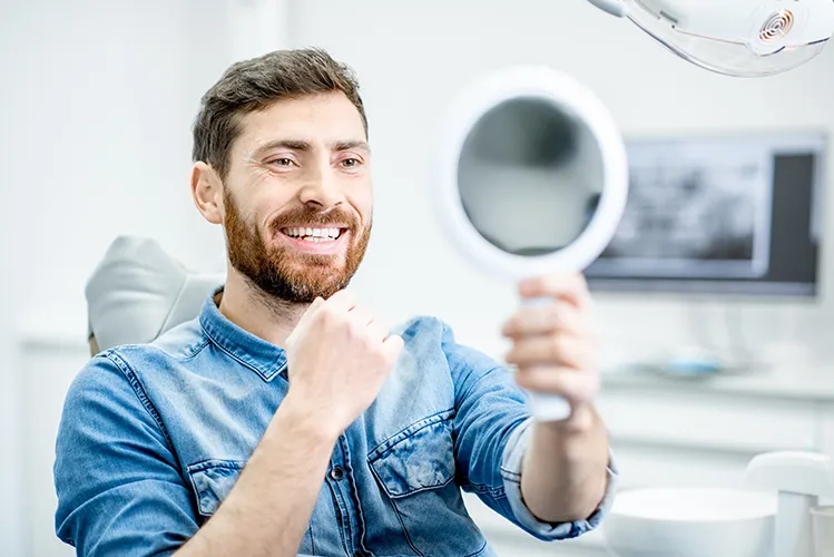 Patient in dental office holding a mirror and smiling - Harmony Family Dentistry in Vancouver WA