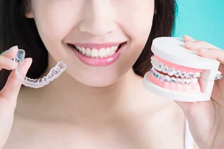 Person holding invisalign and metal braces - Harmony Family Dentistry in Vancouver WA