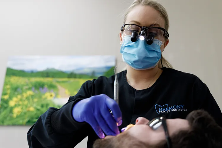 Dental assistant scraping a patient's teeth - Harmony Family Dentistry in Vancouver WA