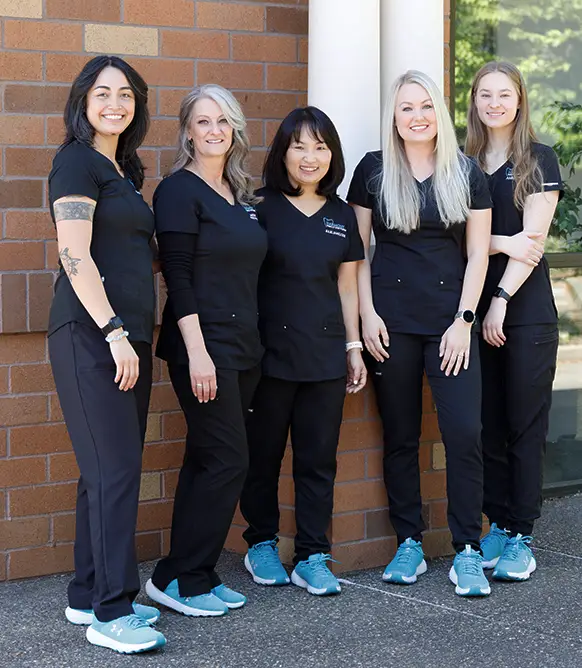 Harmony Family Dentistry staff standing in front of their dental office, all smiling and wearing professional attire - Harmony Family Dentistry in Vancouver WA