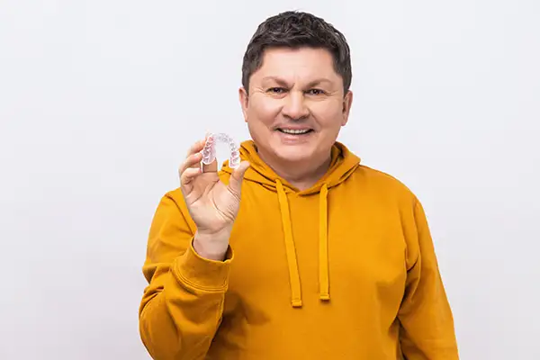 middle age man holds his clear plastic aligners before embarking on Invisalign treatment in Vancouver WA