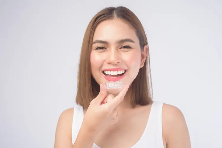 Young Smiling Woman Holding Invisalign Aligners Over White Background Studio After Dental Healthcare and Orthodontic Appointment